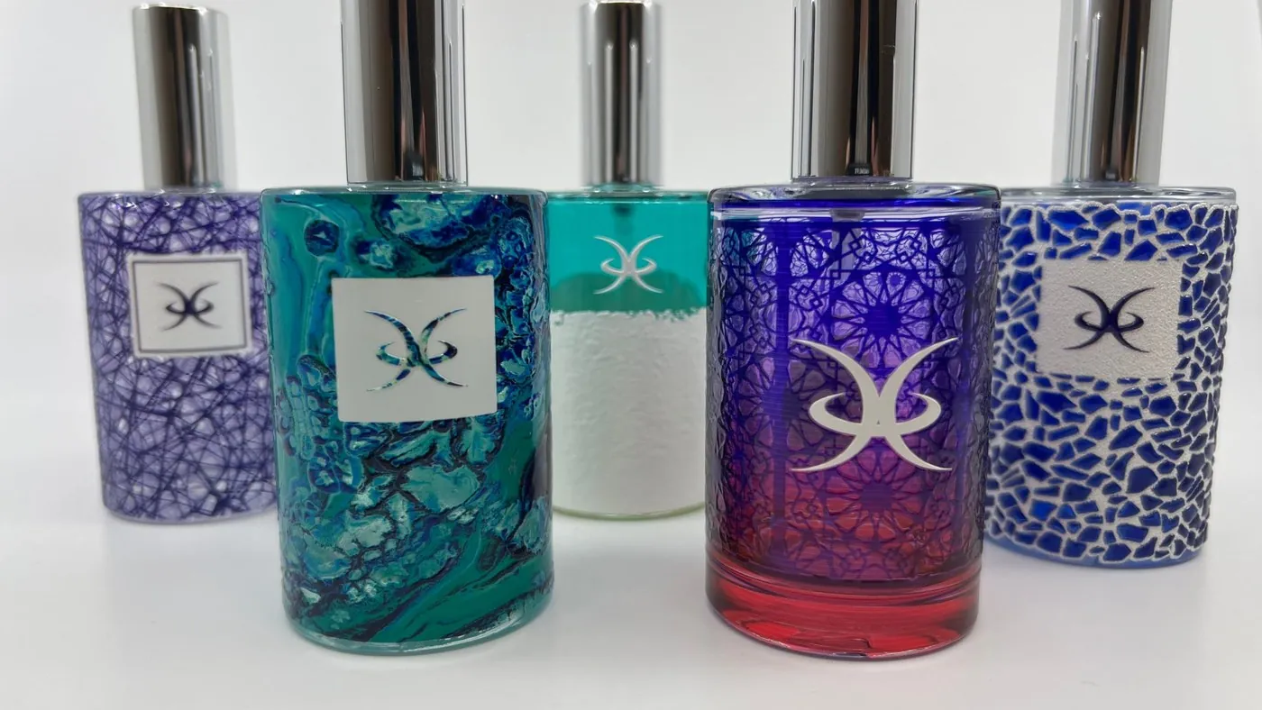 Five perfume bottles printed with patterned colour and a white logo panel
